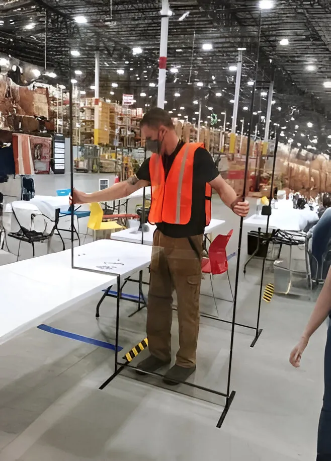 facility maintenance worker in an orange safety vest install a black metal barrier