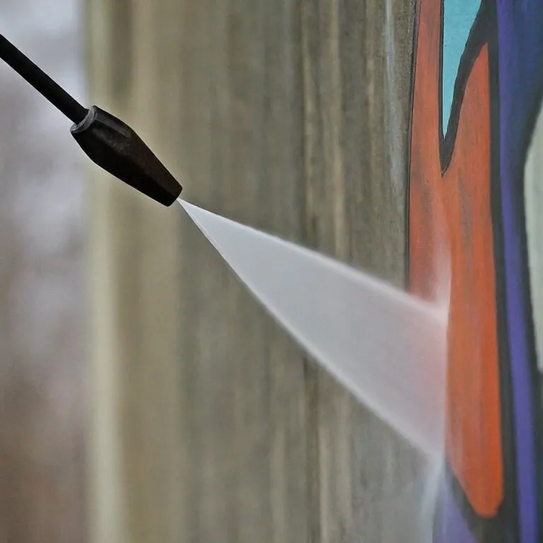 high-pressure water jet being used for graffiti removal on a concrete wall