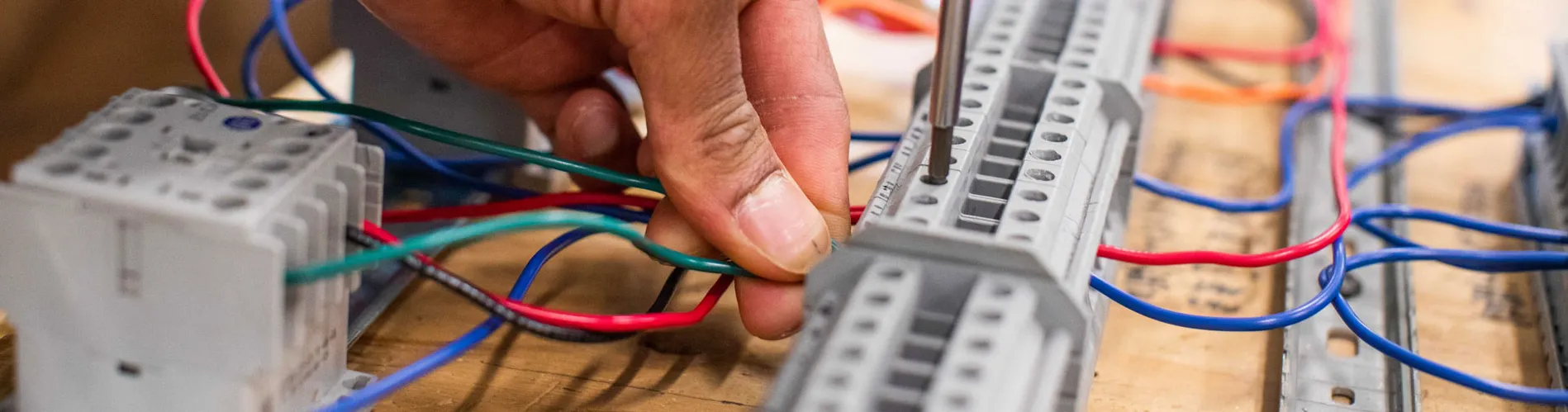 electrician's hand connecting colorful wires to a terminal block